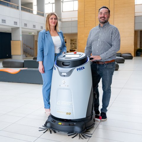 Varga Klaudia, az Uni-Famulus Kft. ügyvezetője és Patvaros Gábor, a PrexRobot értékesítési vezetője a Széchenyi István Egyetemen üzembe helyezett autonóm takarítórobottal. (Fotó: Adorján András/Széchenyi István Egyetem)
